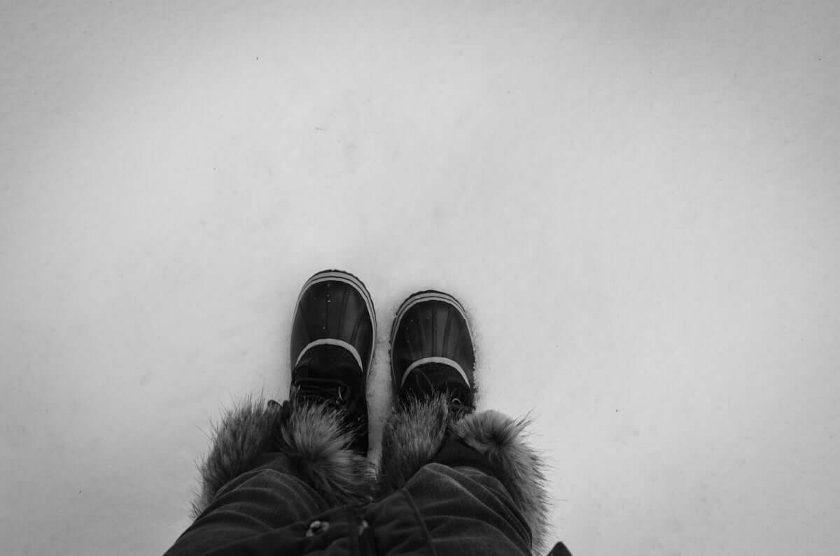 A pair of black shoes sitting on top of a snow covered ground