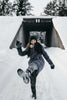 woman in black jacket and blue denim jeans lying on snow covered ground during daytime