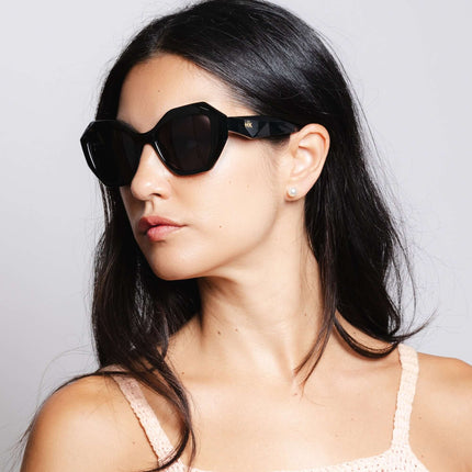 Mujer usando gafas de sol Hanukeii® Moorea Black / Black con montura negra y lentes oscuros.