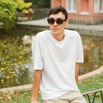 Joven con gafas de sol Hanukeii® Islander Green / Black junto a un estanque en un día soleado.