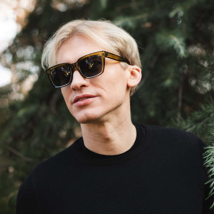 Hombre con gafas de sol Hanukeii® Noosa Green/Black en un entorno natural, destacando un estilo moderno.