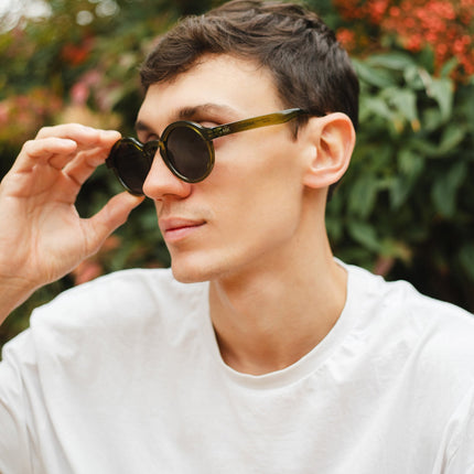 Joven usando gafas de sol Hanukeii® Harbor Green / Black en un entorno natural.